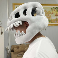 Person wearing a large white dinosaur costume headpiece indoors.